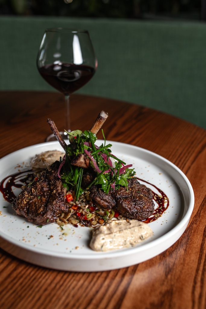 Baharat Lamb Chops Baharat Lamb Chops over wild rice, served on a plate, with a glass of wine