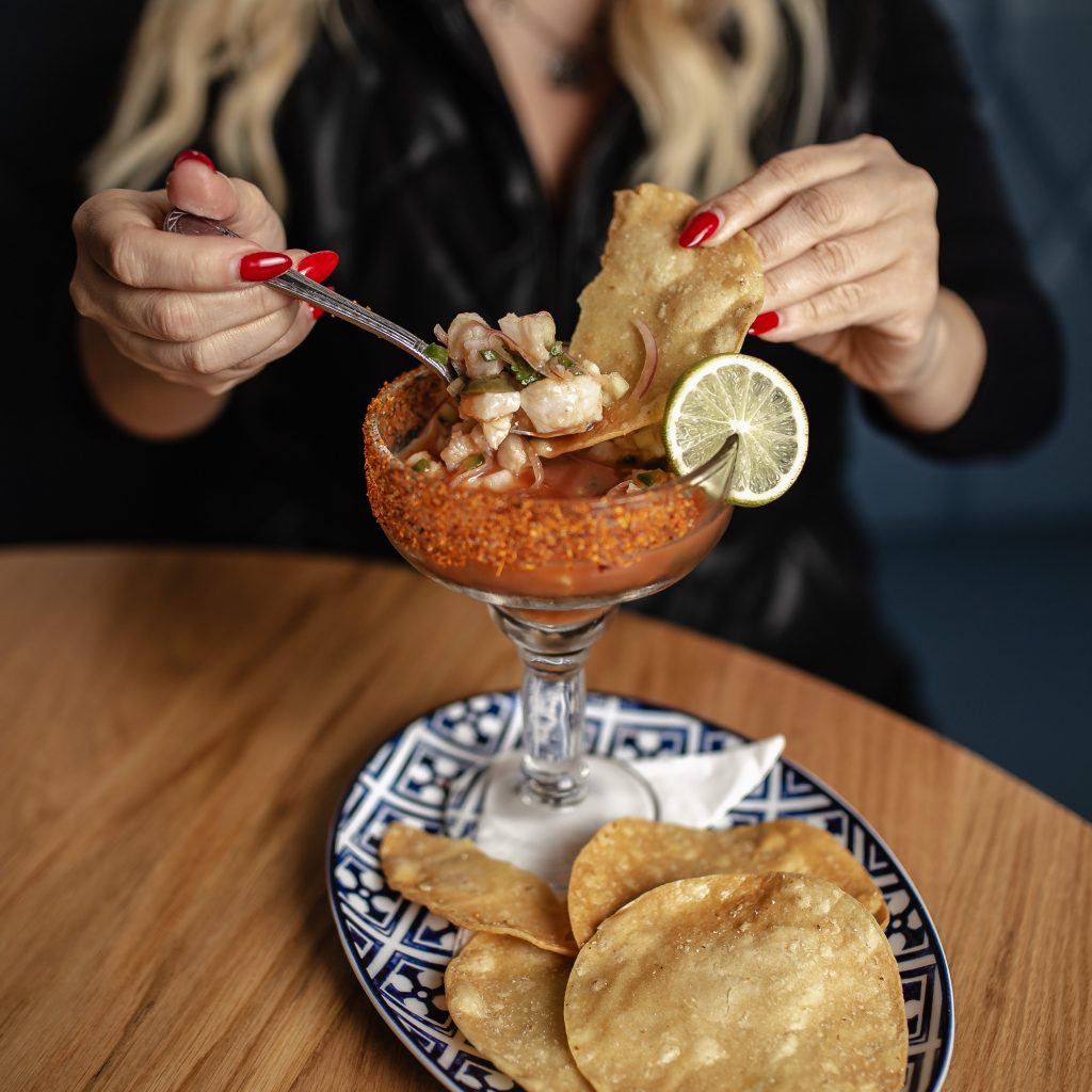 Bloody Mary Ceviche Guest enjoying Bloody Mary Ceviche with tortilla chips