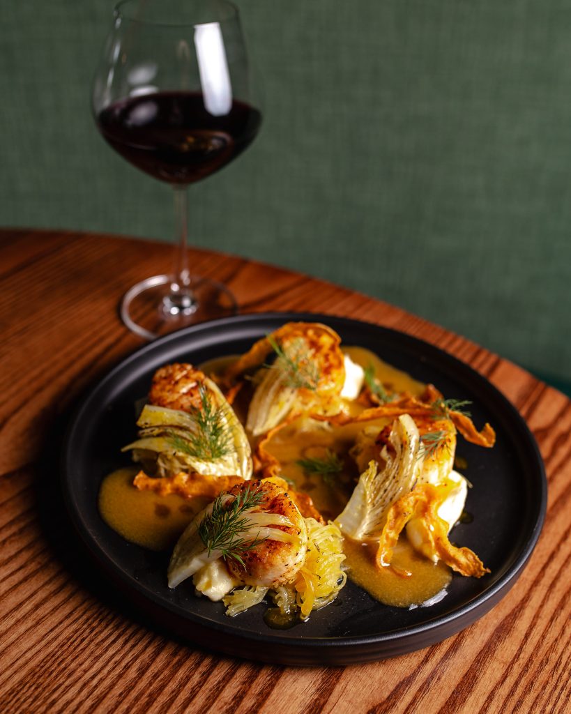 Orange Miso Seared Scallops Orange Miso Seared Scallops served on plate with a glass of wine