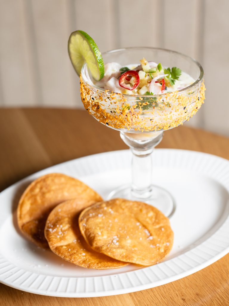 Chili Colada Ceviche in a stemmed glass, with a side of tortilla chips