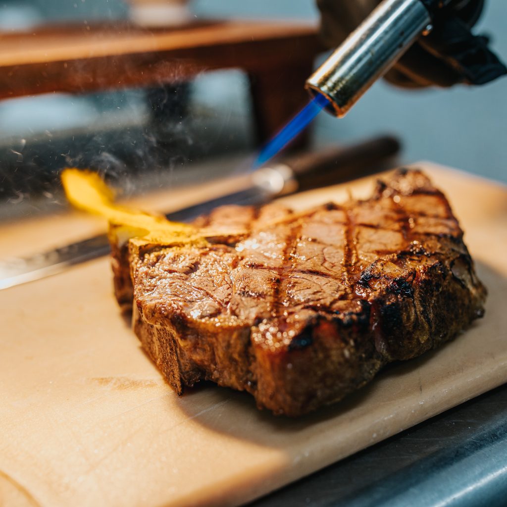 Porterhouse steak being prepared by final searing