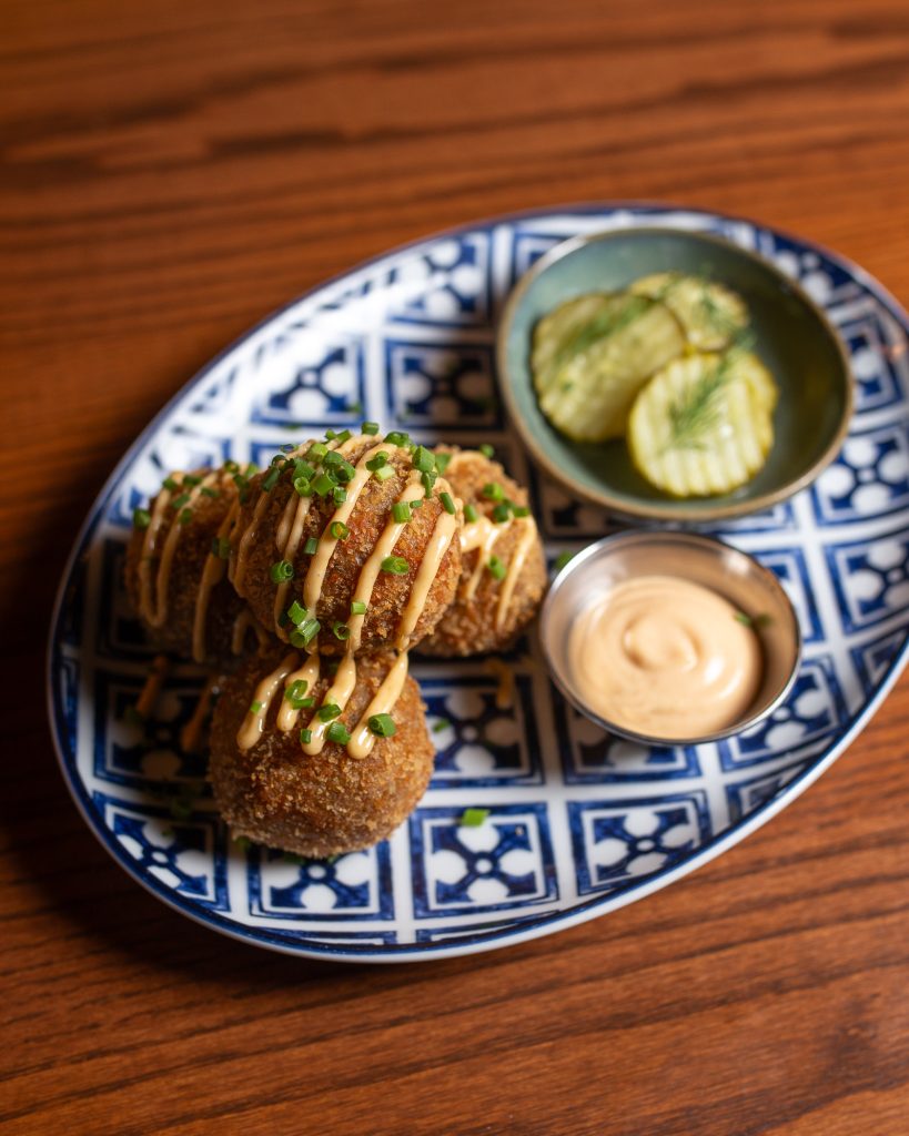 Boudin Bites on a plate, with dipping sauce and pickles
