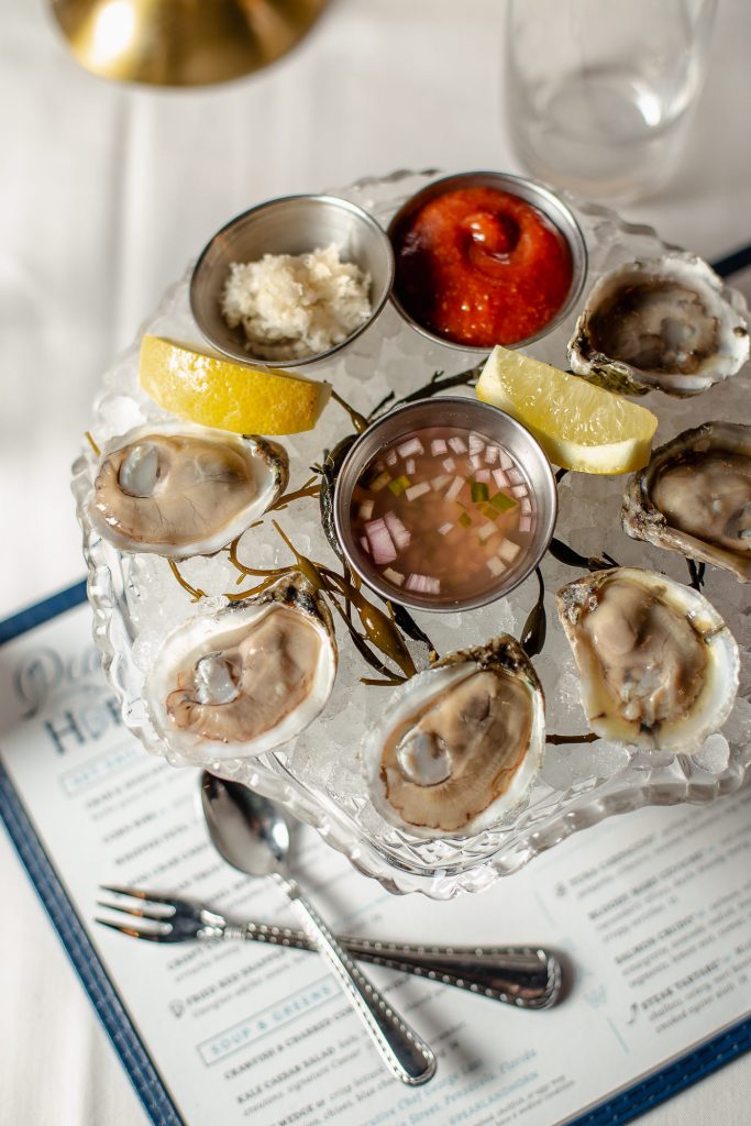 Fresh shucked oysters on ice with lemon, fresh grated horseradish, cocktail sauce, and mignonette